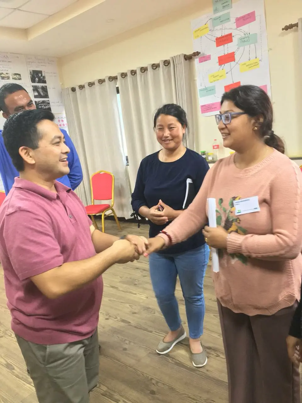 Team members greeting each other warmly at an indoor training event